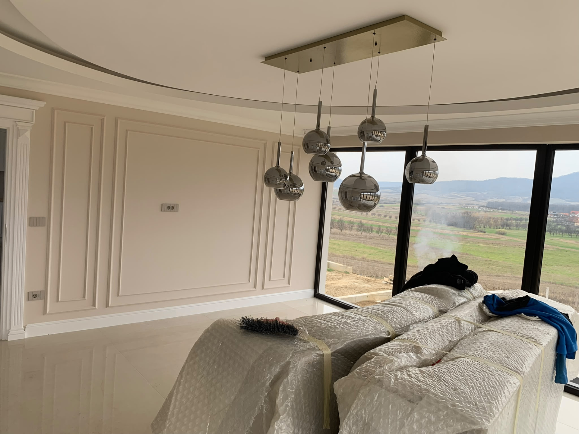 Living cu tavan circular, lambriuri decorative și candelabru cromat modern