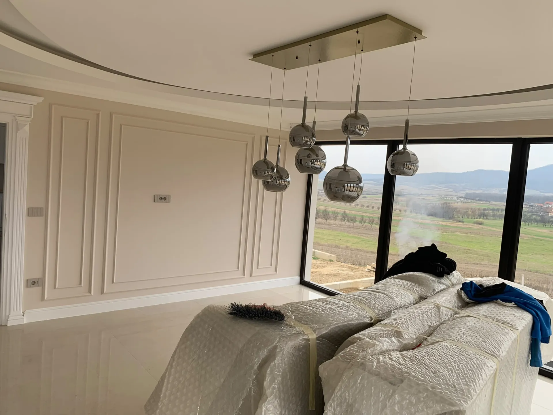 Living cu tavan circular, lambriuri decorative și candelabru cromat modern