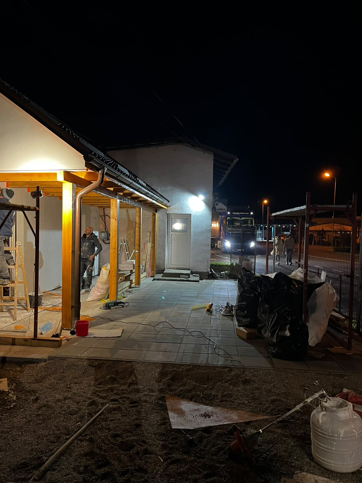 Lucrări nocturne la terasă cu structură nouă din lemn și pavaj montat