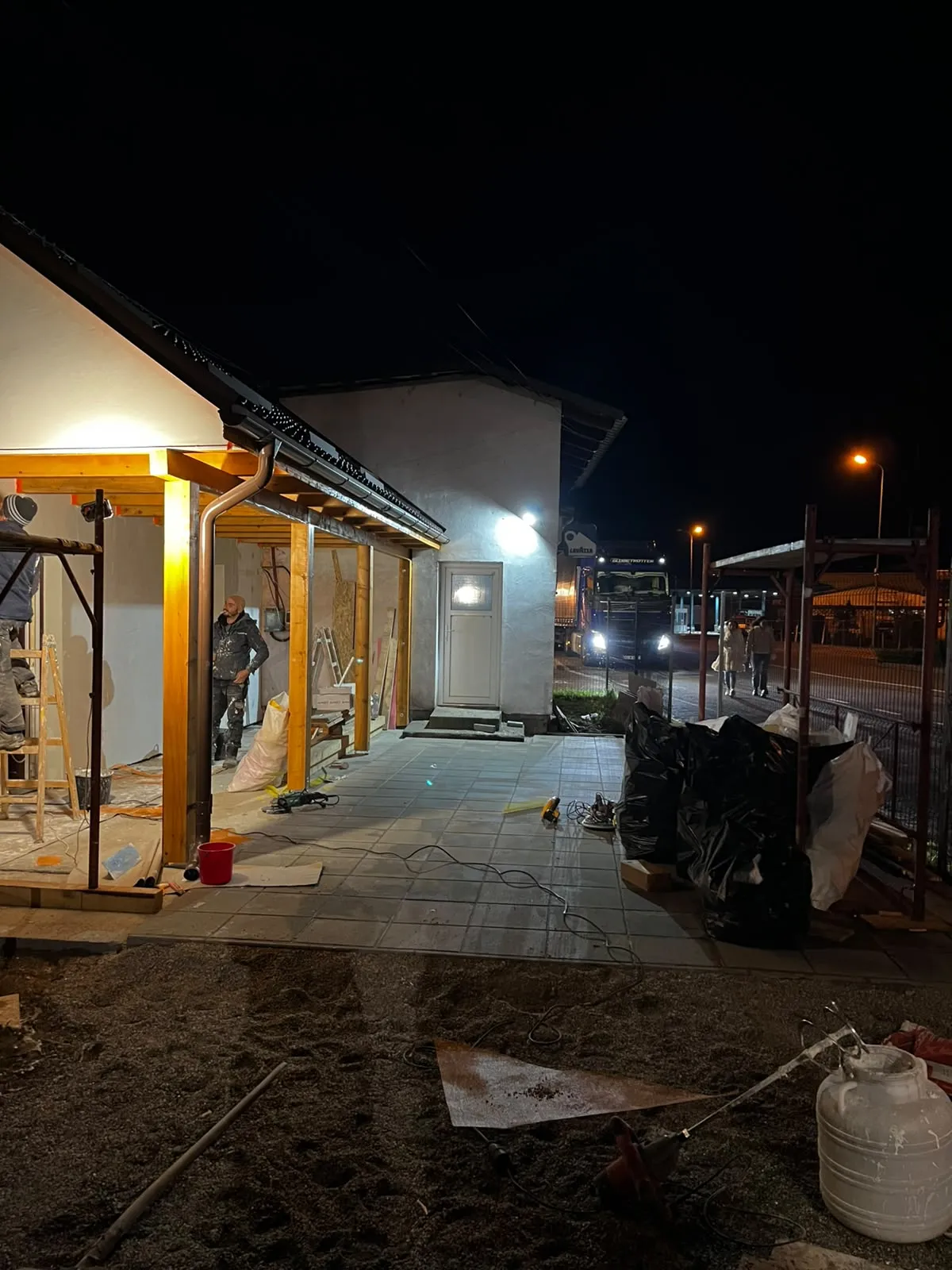 Lucrări nocturne la terasă cu structură nouă din lemn și pavaj montat