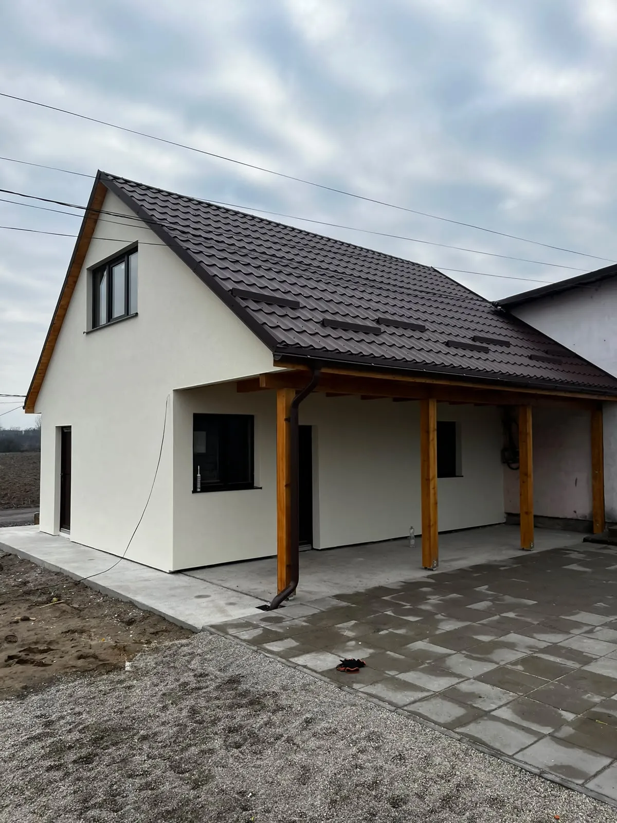 Fațada finalizată cu tencuială albă, acoperiș nou și terasă acoperită