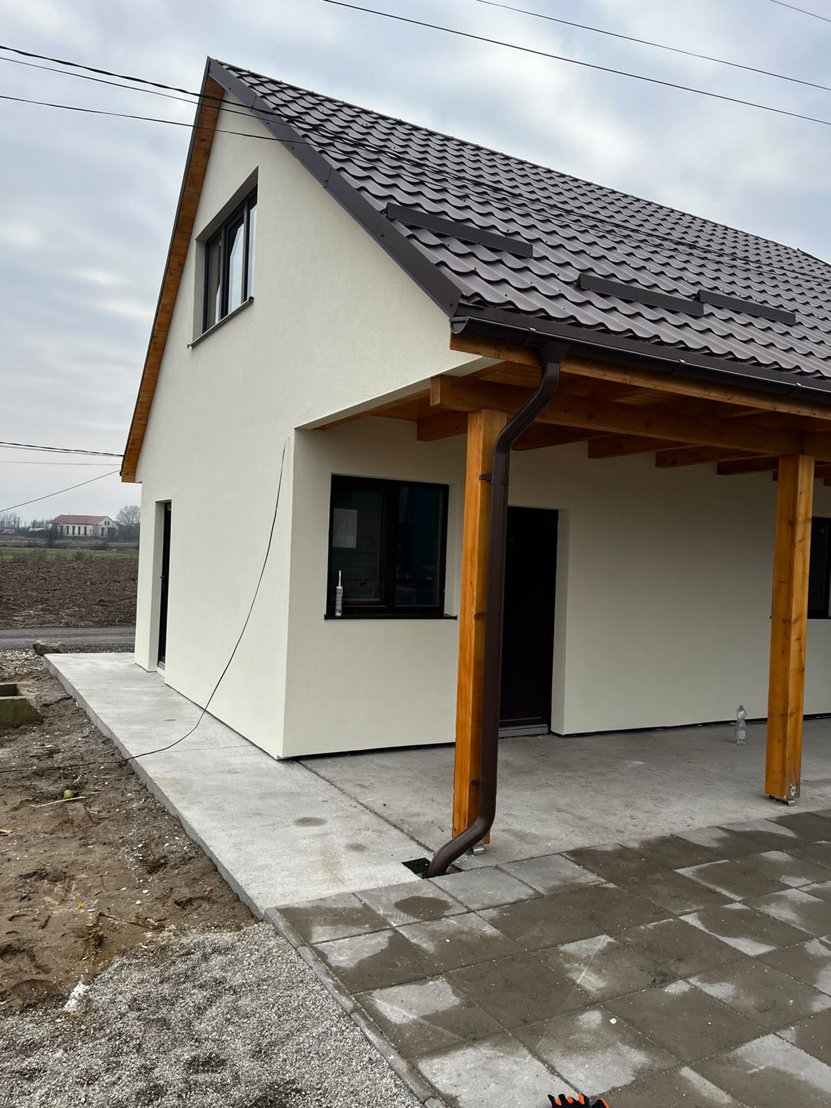Vedere laterală a casei renovate cu stâlpi din lemn și jgheaburi noi